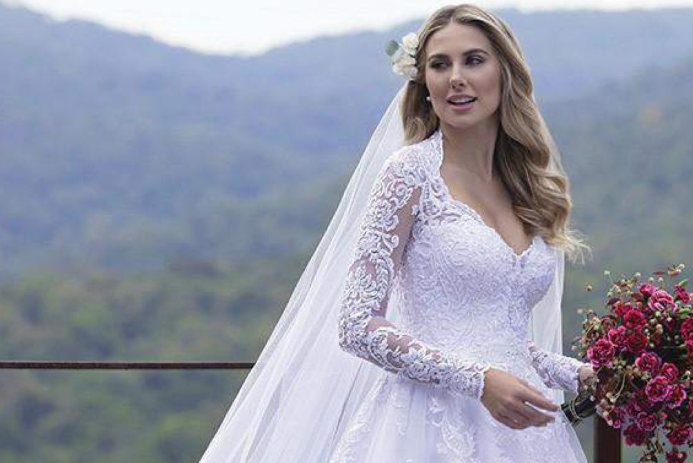 Vestido rodado com decote princesa e mangas longas; Vestido em tule com barrado e aplicações de renda fio de seda, bordadas com paetês; Renda do corpo do vestido bordadas com pedrarias diversas. Broche fixo bordado com cristais diversos. Transparência branca. [ngg src=”galleries” ids=”13″ display=”basic_thumbnail” thumbnail_crop=”0″]