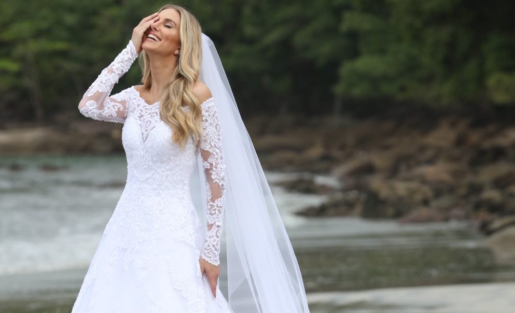 Vestido evase, decote ombro a ombro (branco/off white), manga longa. Vestido em net paetizada, sobreposta por tule com barrado e aplicações de renda soutache. Corpo bordado com vidrilhos e missangas. [ngg src=”galleries” ids=”10″ display=”basic_thumbnail” thumbnail_crop=”0″]