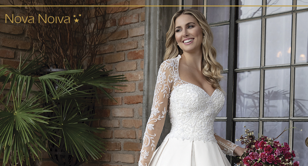 Vestido ivory rodado com decote princesa e mangas longas; Vestido em cetim com saia em pregas; Corpo do vestido bordado com cristais e pedrarias diversas; Botões de cristais; Transparência nude. [ngg src=”galleries” ids=”22″ display=”basic_thumbnail”]